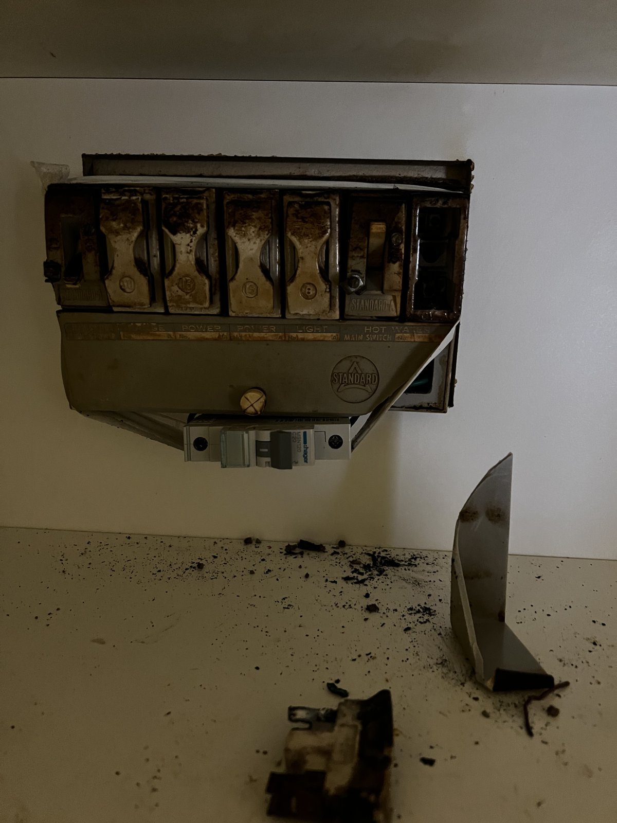 Old burnt ceramic fuse switchboard with debris below